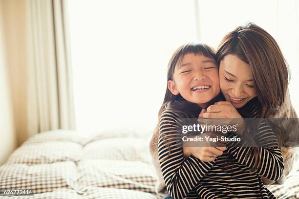 mutter und tochter spielen im schlafzimmer - mama kind kuscheln stock-fotos und bilder