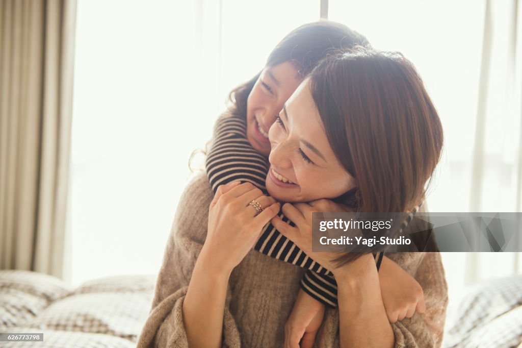 Mother and daughter playing in bed room