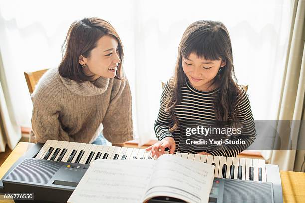 mother and daughter playing  on electronic piano - electric piano stock pictures, royalty-free photos & images