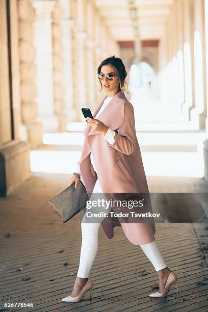 schöne elegante frau sms im freien - pink coat stock-fotos und bilder