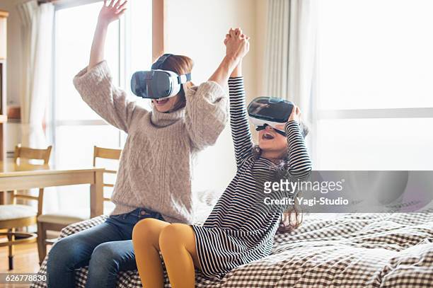 mutter und tochter spielen in virtual-reality-brille im schlafzimmer - asia child glasses stock-fotos und bilder