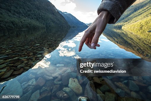 Finger touches surface of mountain lake, New Zealand Finger touches surface of mountain lake, New Zealand