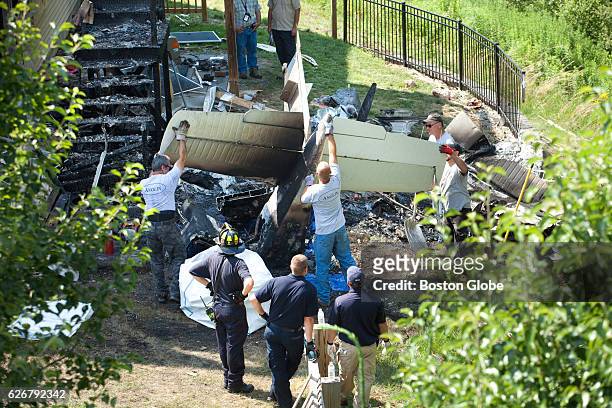 Investigators from the National Transportation Safety Board photograph a plane crash site in Plainville, MA on Jun. 30, 2015 as salvage crews remove...