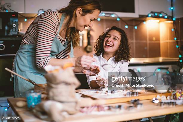 mother and daughter making gingerbread cookies for christmas - holiday baked goods stock pictures, royalty-free photos & images