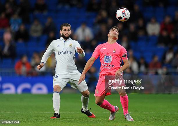 Angel Bastos of Cultural Leonesa heads the ball in front of Nacho of Real Madrid CF during the Copa del Rey last of 32 match between Real Madrid and...