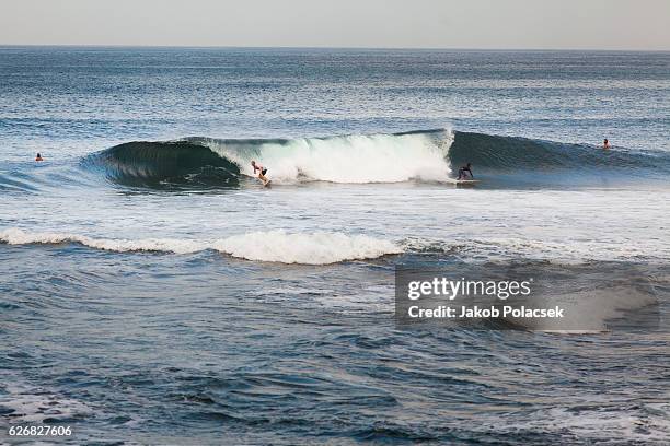 two surfers surfe an a-frame shaped wave in bali - surfe stock pictures, royalty-free photos & images