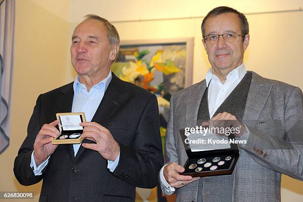 Latvia - Latvian President Andris Berzins and Estonian President Toomas Hendrik Ilves hold euro coins they exchanged in Rujiena, Latvia, on Jan. 2,...