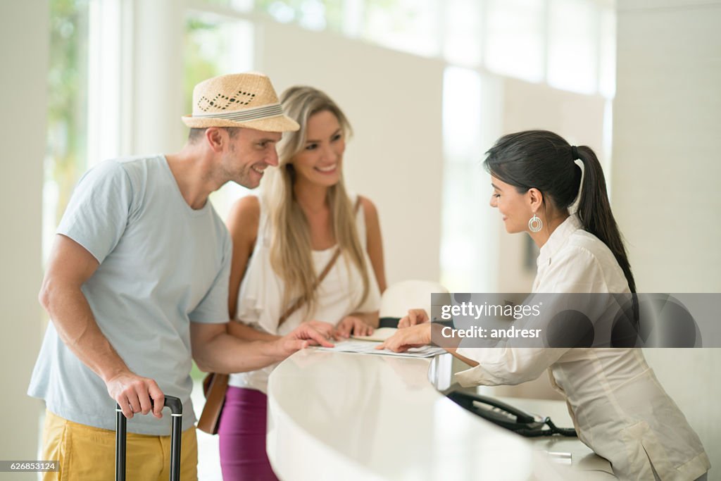 Hôtesse de l’hôtel aidant couple avec l’enregistrement