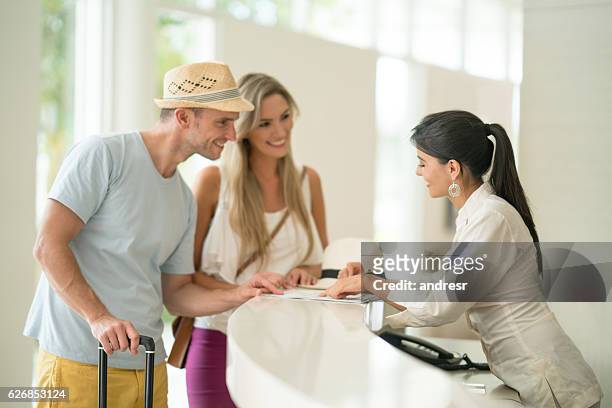 hotel hostess helping couple with the check-in - travel service stockfoto's en -beelden