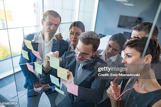 es geht um innovation und neue geschäftsideen - team looking at adhesive notes in board room during meeting stock-fotos und bilder