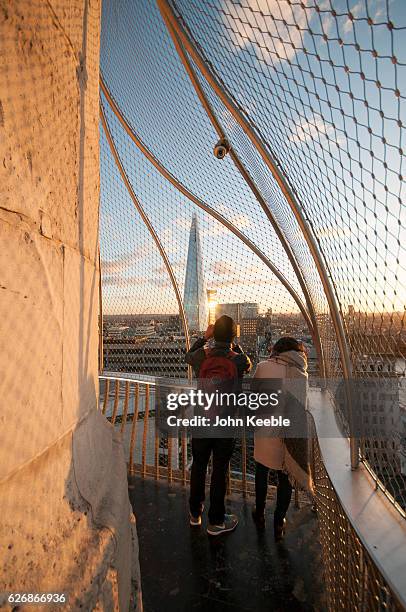 Tourists at the top of the Monument to the Great Fire of London look out and take pictures of the Shard building as the sun sets on November 28 in...