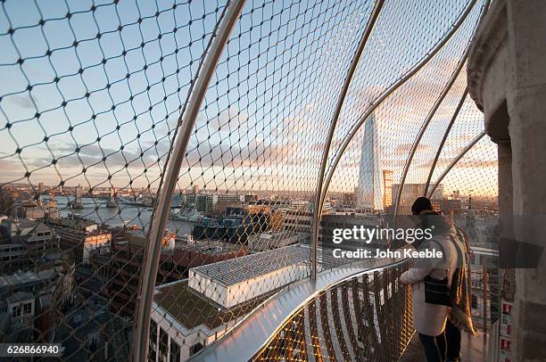 Tourists at the top of the Monument to the Great Fire of London look out toward the Shard building as the sun sets on November 28 in London United...