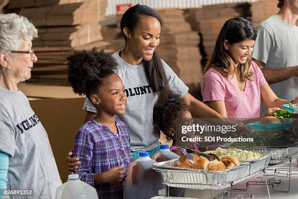 diverse family volunteers together in soup kitchen - homelessness help stock pictures, royalty-free photos & images