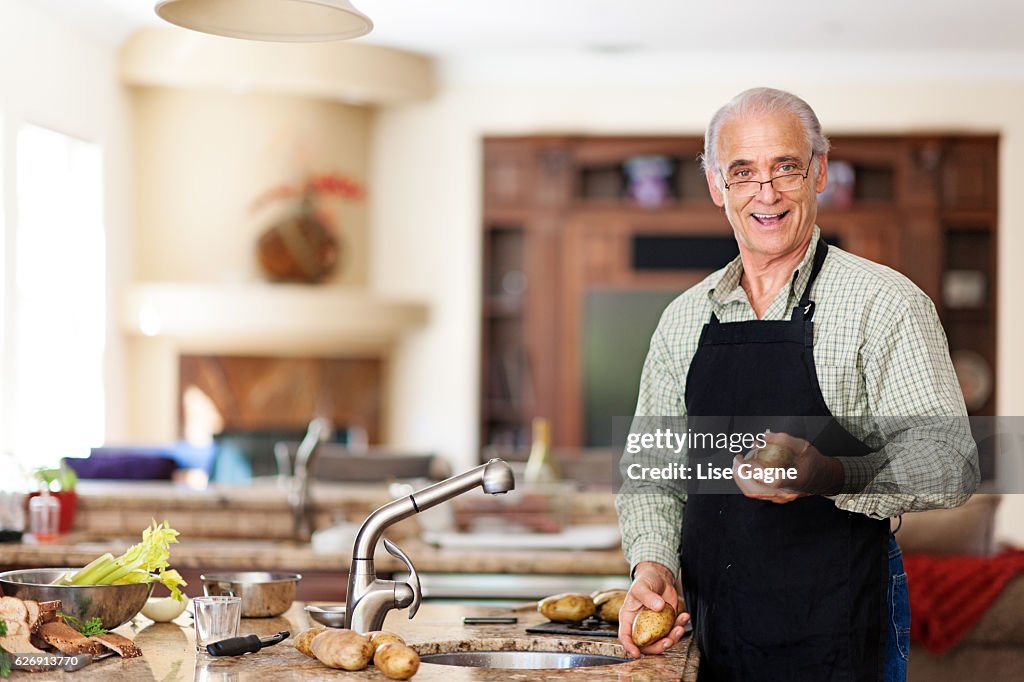 Senior Mann bereitet sich auf Kartoffeln zu waschen