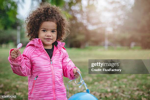 cute toddler with afro hair, holding lollipop - pink jacket stock pictures, royalty-free photos & images