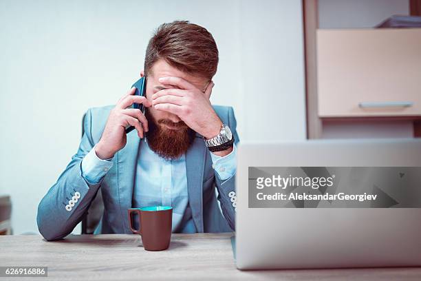 uomo d'affari preoccupato ed esausto che parla al telefono nel suo ufficio - ragazzo disperato telefono foto e immagini stock