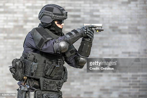 swat police officer against brick wall - special forces stockfoto's en -beelden