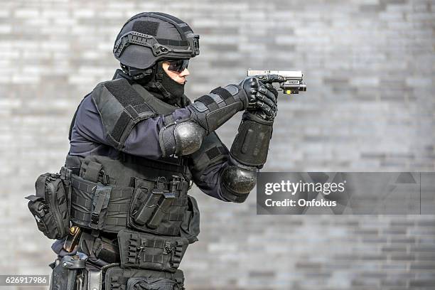 swat police officer against brick wall - anti terrorism stock pictures, royalty-free photos & images