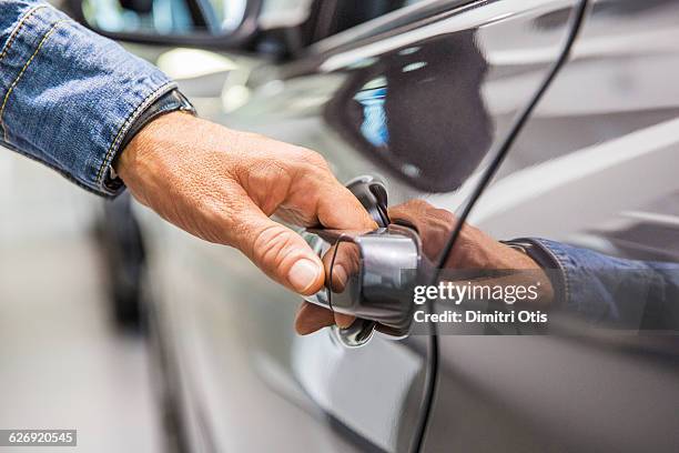 man's hand on grey car door handle - manette foto e immagini stock