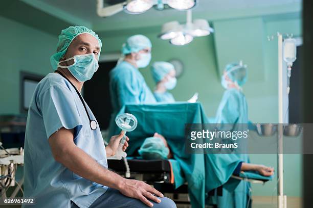 mid adult anesthesiologist during surgery in operating room. - anesthesiologist imagens e fotografias de stock