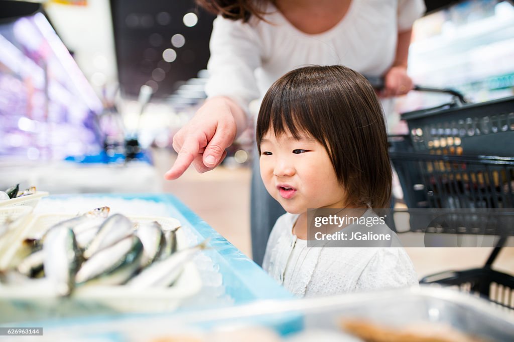 Junges Mädchen, das Fisch in einem Supermarkt anschaut