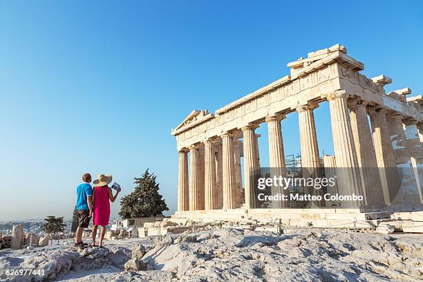 couple looking at parthenon temple, athens, greece - athens vacation photos et images de collection