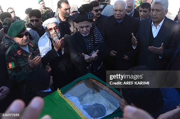 Afghan President Ashraf Ghani prays over the coffin of commander of the 207th Corps, General Mohayedin Ghori in Herat on December 1, 2016....