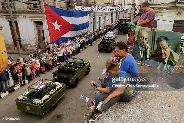 People sit on their rooftop to get a better view as the remains of former Cuban President Fidel Castro pass by on their cross-country journey from...