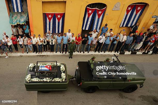 People line the street to make photographs and wave flags as the remains of former Cuban President Fidel Castro pass by on their cross-country...