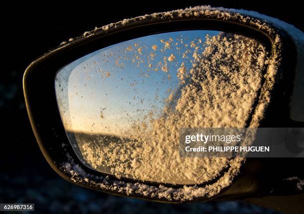 The rear-view mirror of a car is covered with frost at dawn in Caestre, northern France, on December 1, 2016.