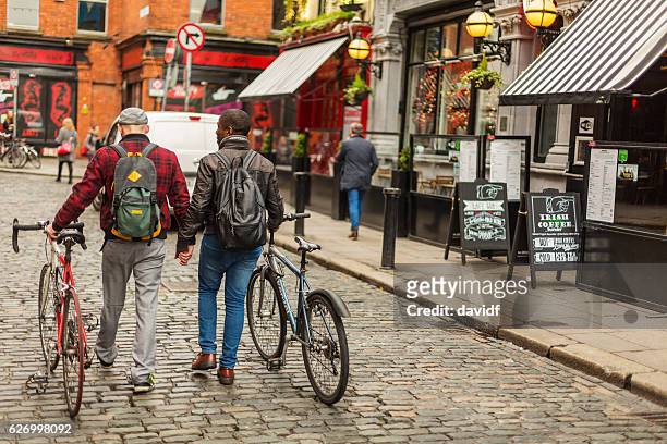 mixed race gay couple with bicycles in the city - dublin street stock pictures, royalty-free photos & images