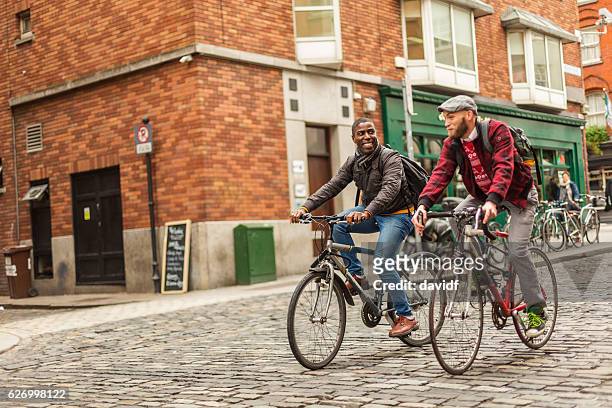 mixed race gay couple with bicycles in the city - dublin city stockfoto's en -beelden
