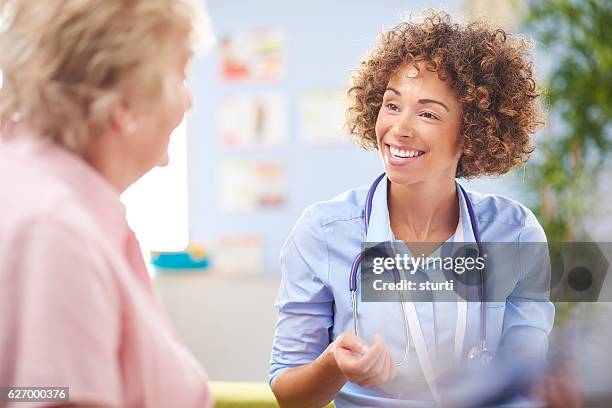 happy gp doctor with senior patient - shirt stock pictures, royalty-free photos & images