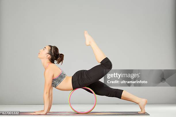 pilates estiramiento entrenamiento yoga rueda posturas mujer practicando yoga avanzado - training wheels fotografías e imágenes de stock