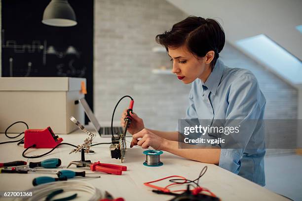 woman soldering a circuit board in her tech office. - voltmeter stock pictures, royalty-free photos & images