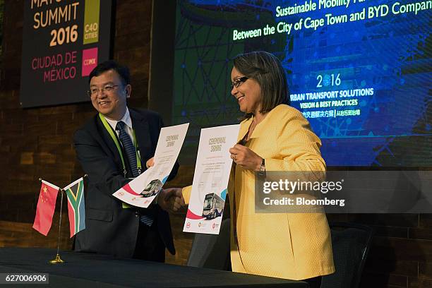 Wang Chuanfu, president of BYD Co., and Patricia de Lille, mayor of Cape Town, hold up signed Sustainable Mobility Partnership agreements during the...