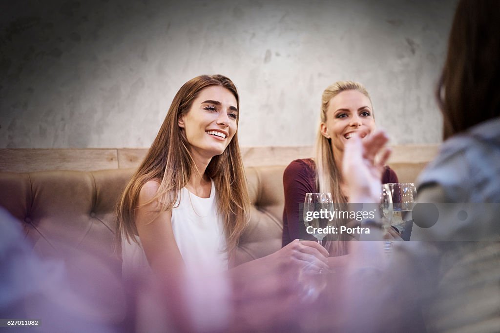 Happy women listening to friend in restaurant