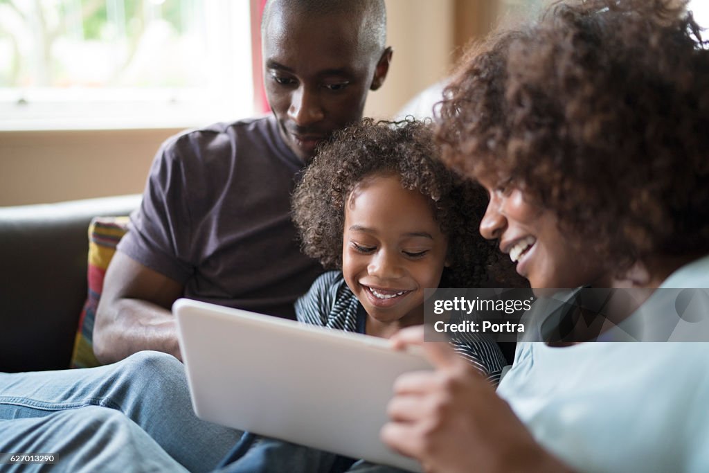 Famille joyeuse utilisant une tablette numérique sur un canapé