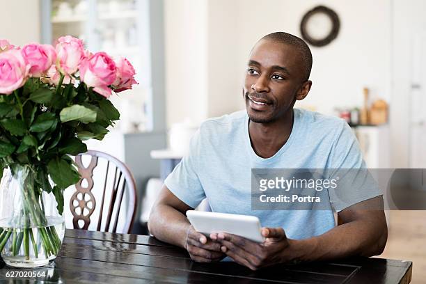 自宅でデジタルタブレットを保持する思慮深い男 - single rose ストックフォトと画像