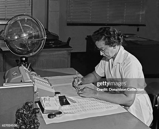 Space scientist, and mathematician Katherine Johnson poses for a portrait at her desk with an adding machine and a 'Celestial Training device' at...