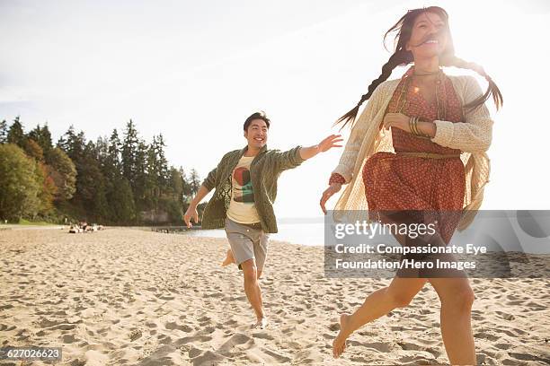 couple playing on beach - barefoot running stock pictures, royalty-free photos & images