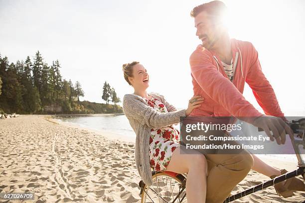 couple enjoying bicycle ride on beach - canadian pacific women stock pictures, royalty-free photos & images