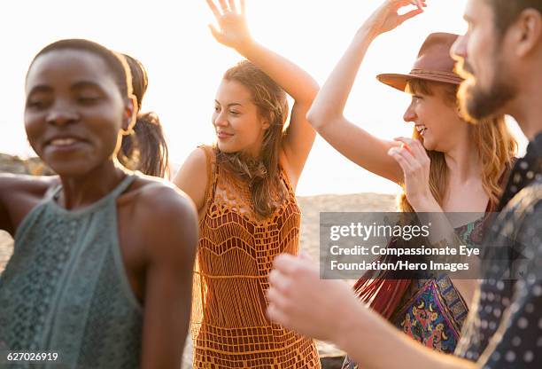 friends enjoying dancing on beach - women in see through dresses stock-fotos und bilder