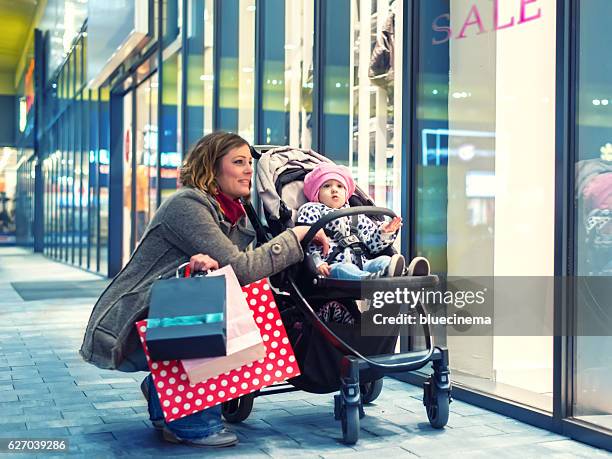 woman with her baby in a shopping mall - baby boutique stock pictures, royalty-free photos & images
