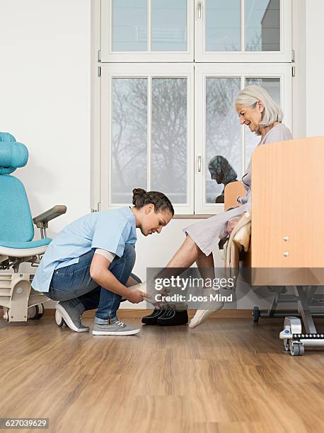 caregiver helping senior woman put on socks - help getting dressed stock pictures, royalty-free photos & images