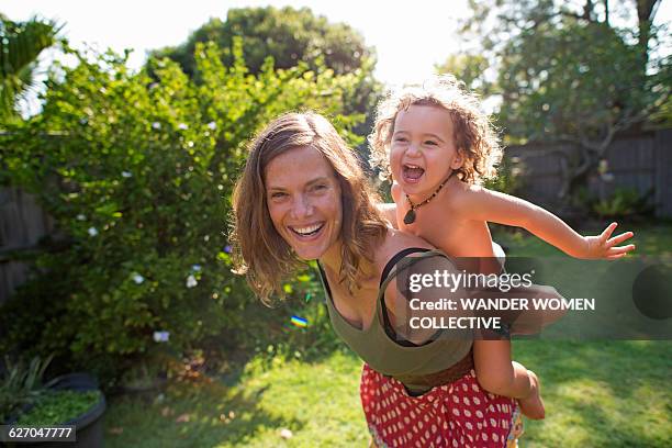 real mother with child flying on back in garden - real people family portraits stockfoto's en -beelden