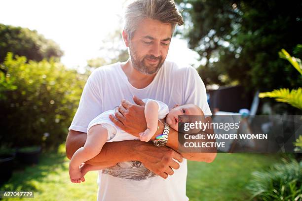 real father holding baby in garden on sunny day - leanincollection father stock pictures, royalty-free photos & images