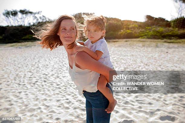 mother with child on back walking sunset on beach - boy in wind stock-fotos und bilder