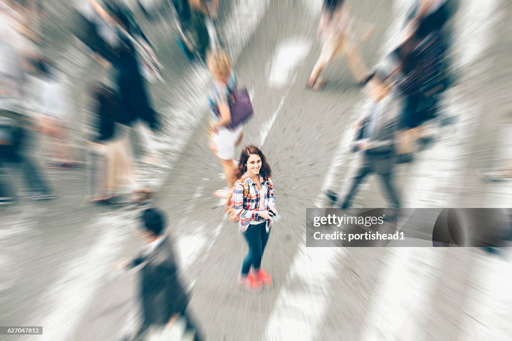 Woman standing in the middle of crowd crossing street