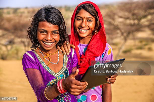 happy indian young girls using digital tablet, desert village, india - childhood poverty stock pictures, royalty-free photos & images